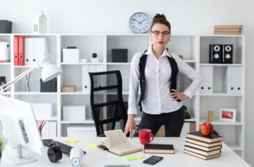 A young girl is standing near a table in the office.