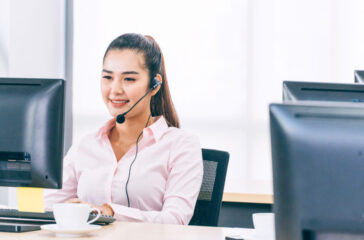 Asian woman call center with headset sitting at office desk
