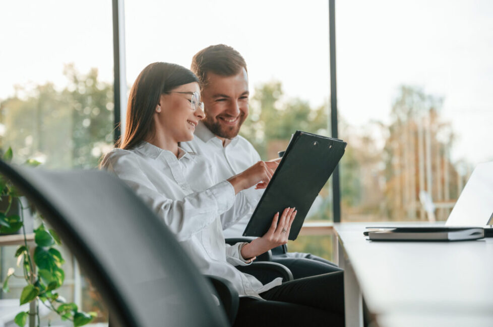 Side view. Man and woman are working in the modern office together Side view. Man and woman are working in the modern office together