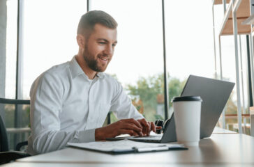 Using laptop. Man in formal clothes is working in the modern office